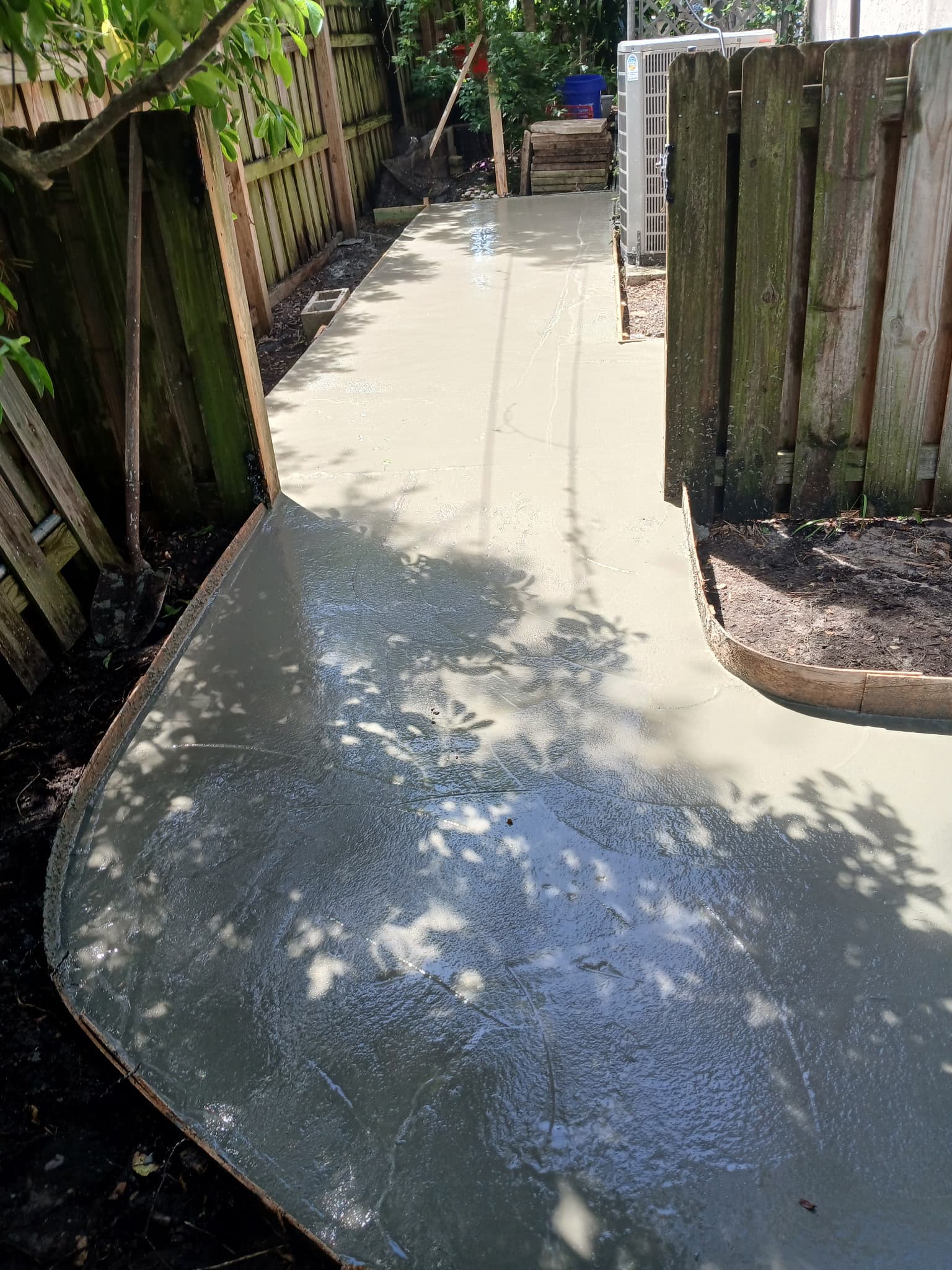 Finished concrete walkway slab running down a side yard toward the backyard gate.